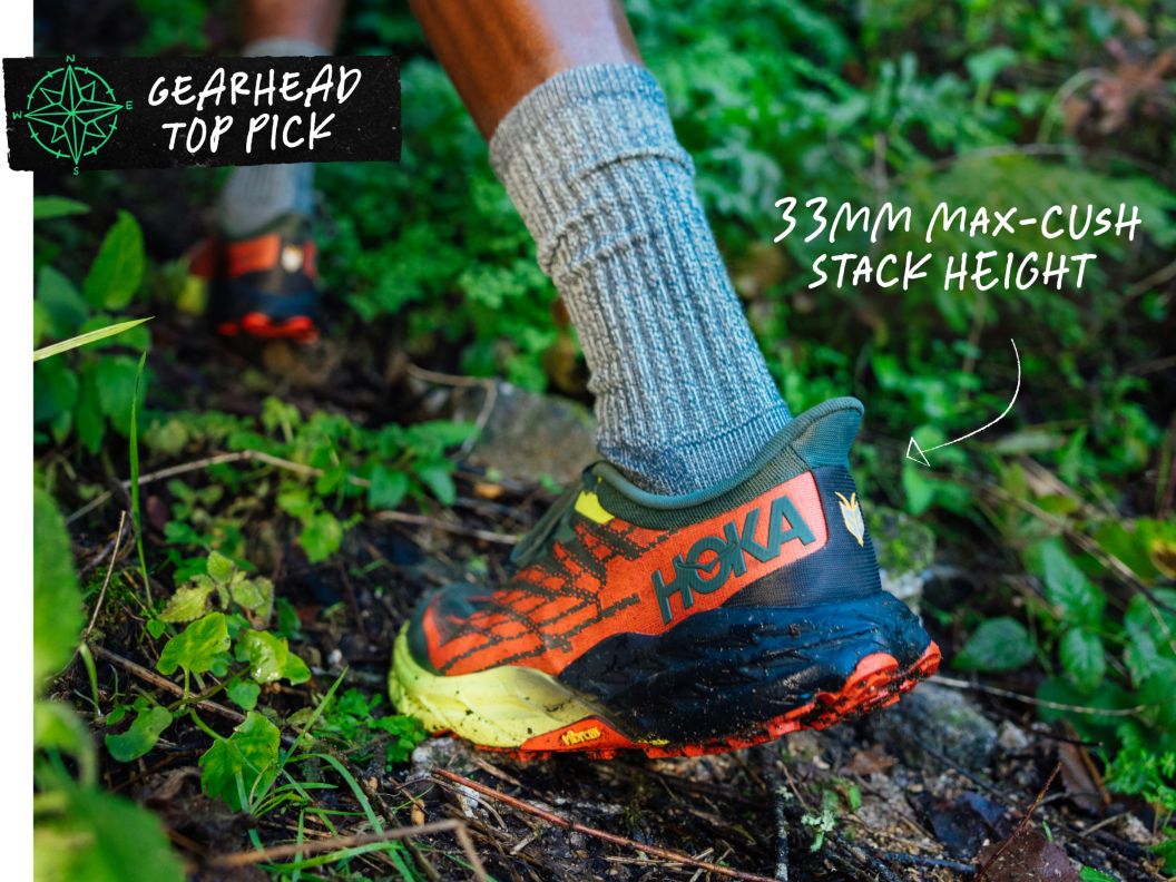 A person walks through brush wearing a brightly colored shoe that says hoka on it. text overlay reads: gearhead top pick, 33mm max-cush stack height.